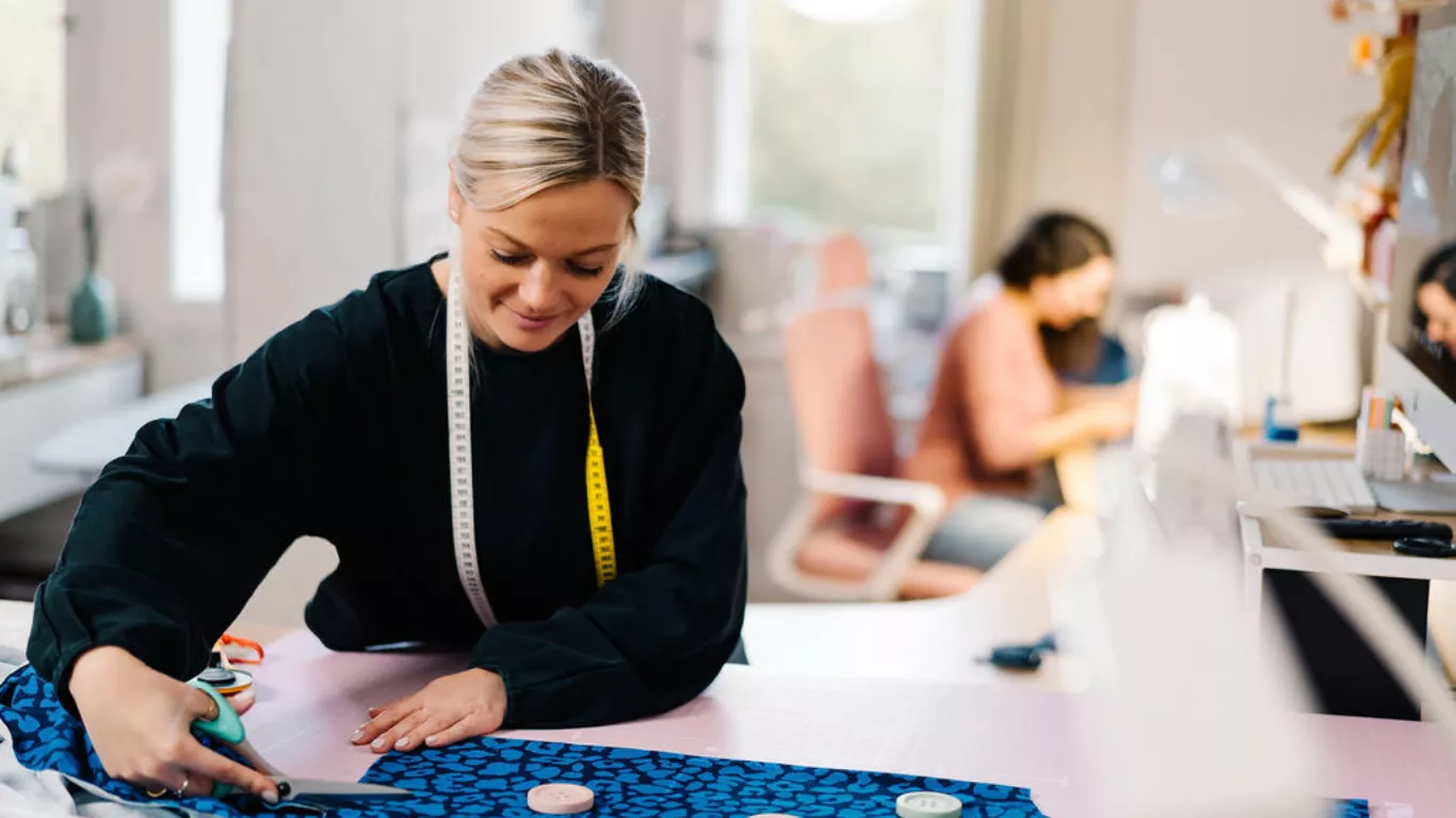 Lybstes Schnittmuster Atelier - Stoff wird zugeschnitten und im Hintergrund genäht