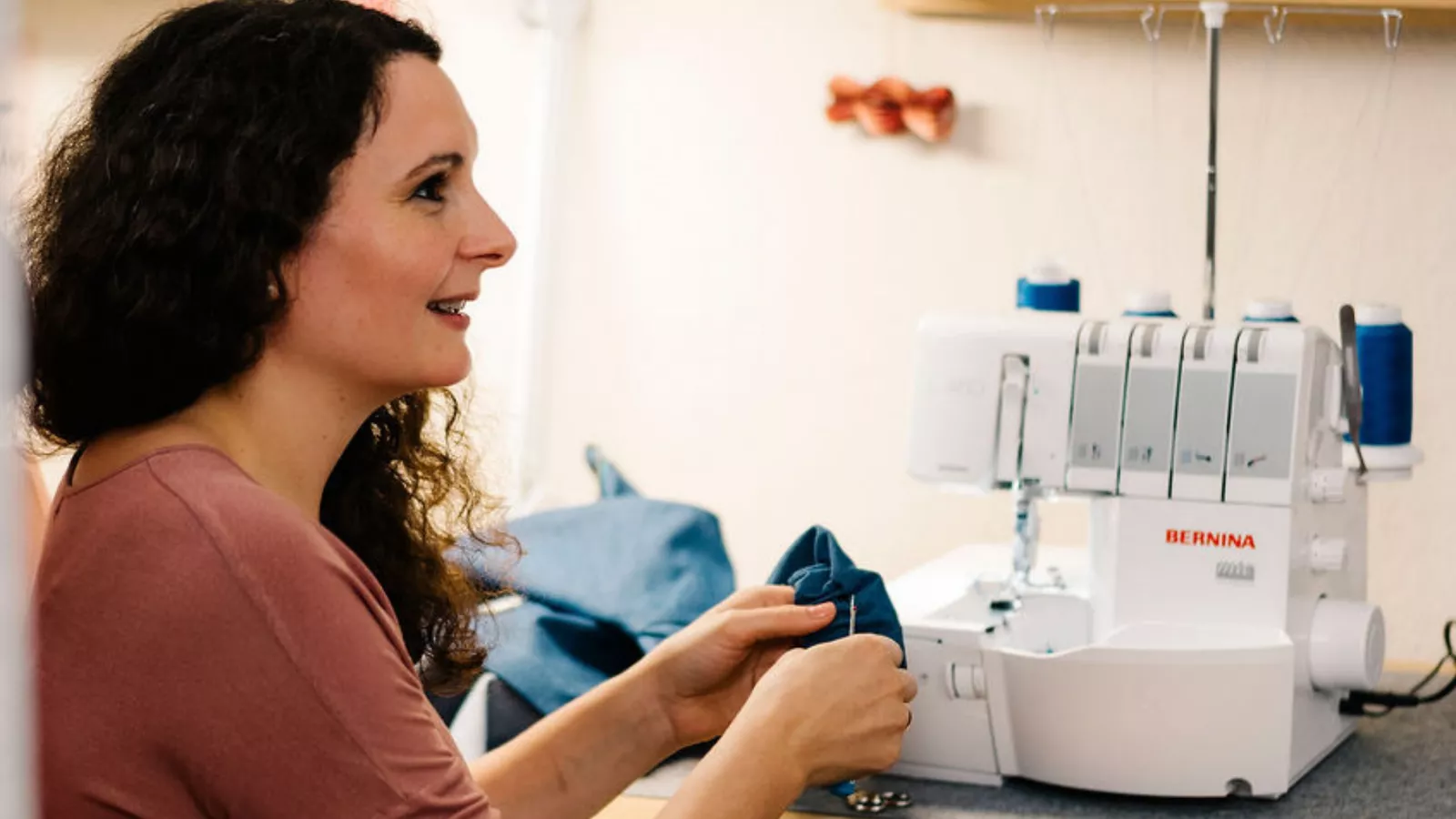 Frau sitzt vor einer Nähmaschine mit blauem Jeansstoff